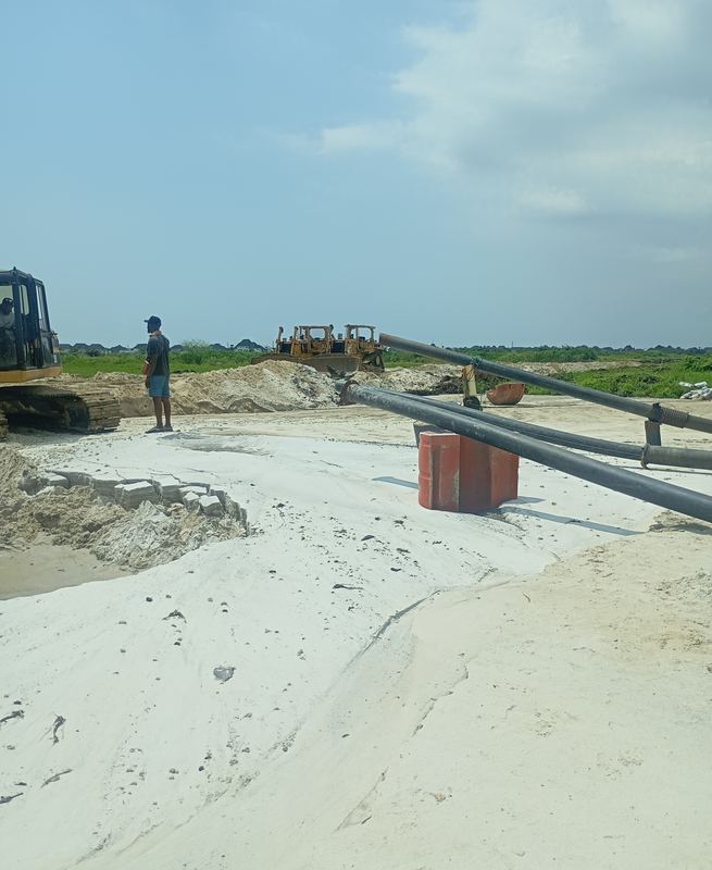 Dredge discharge lines delivering sand fill to the platform